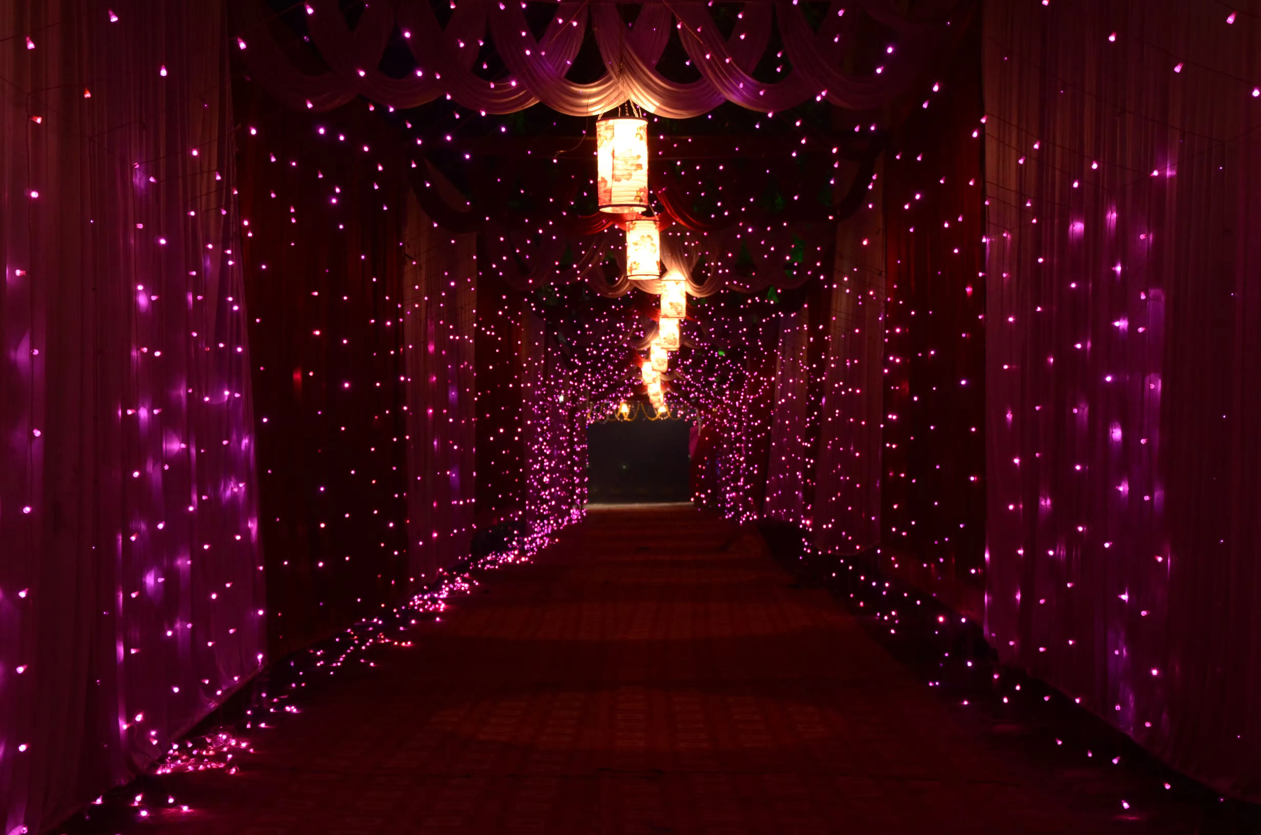 A lit pathway created with layered string lighting and lanterns