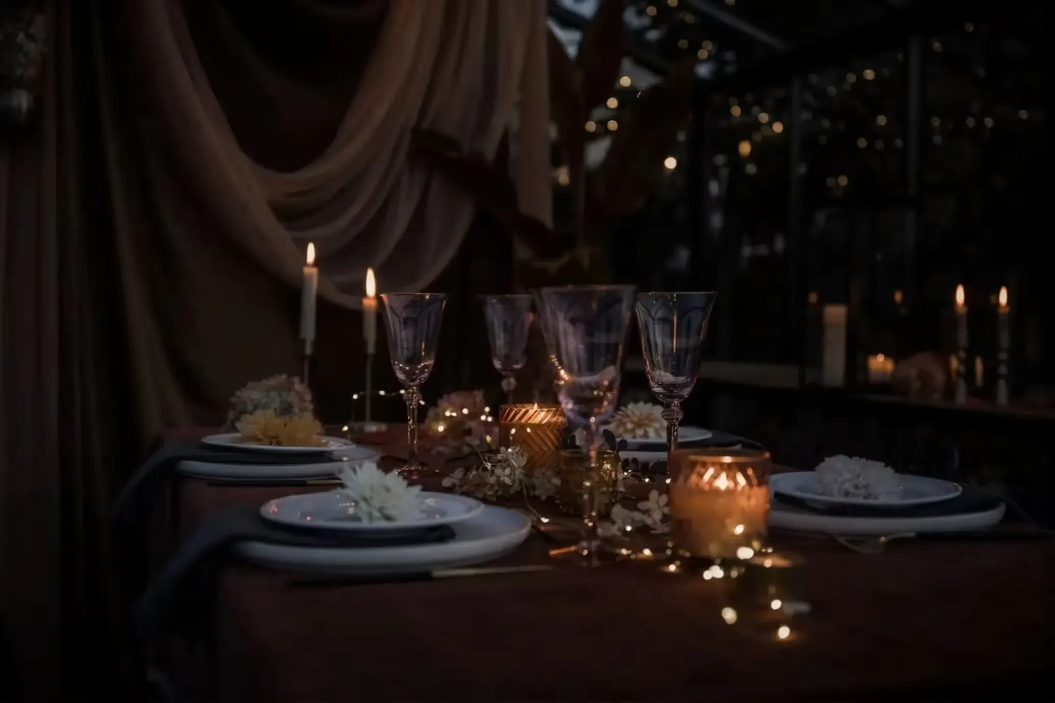 A candlelit table setting glowing softly in the evening