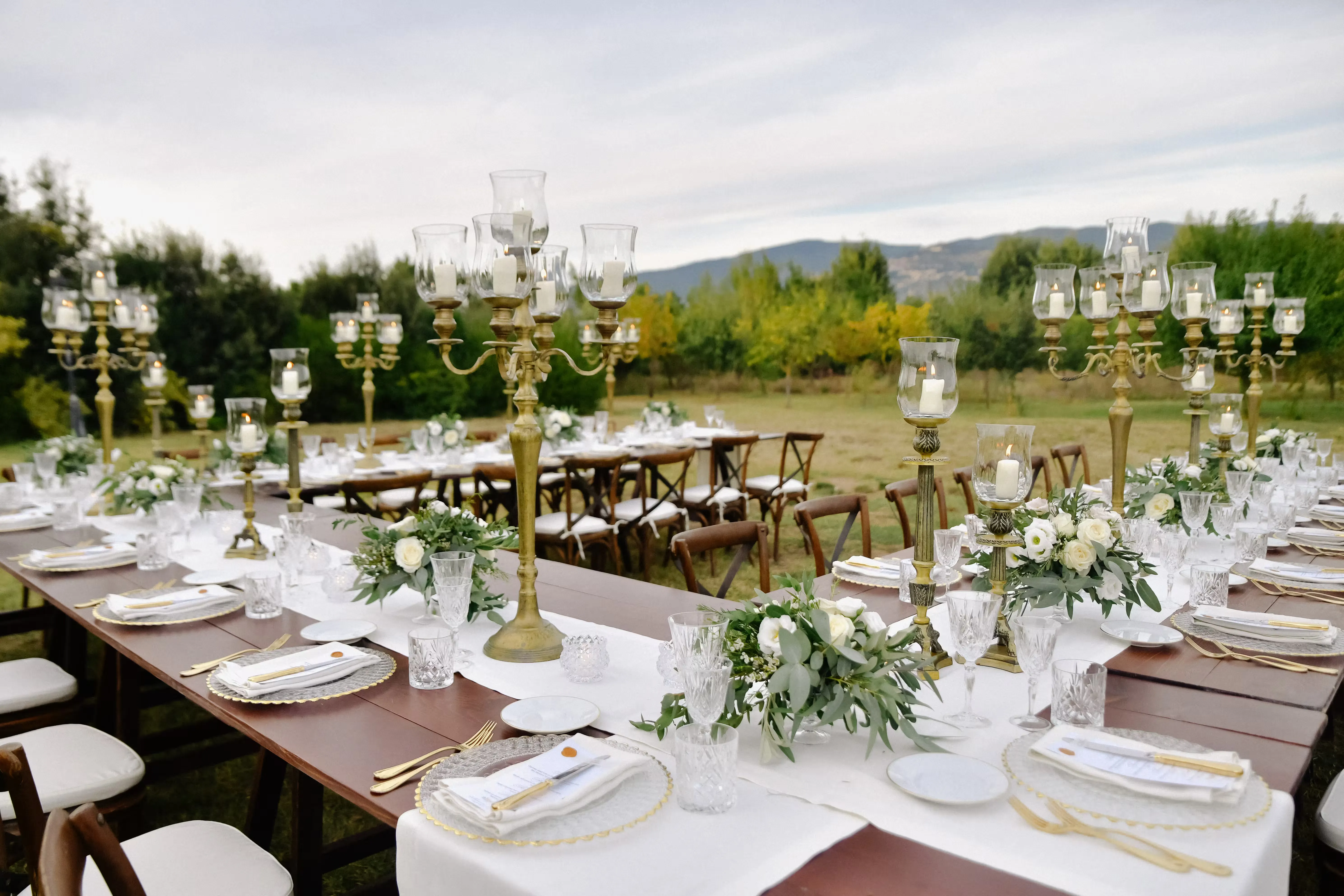 A long table styled with a continuous floral runner and matched glassware